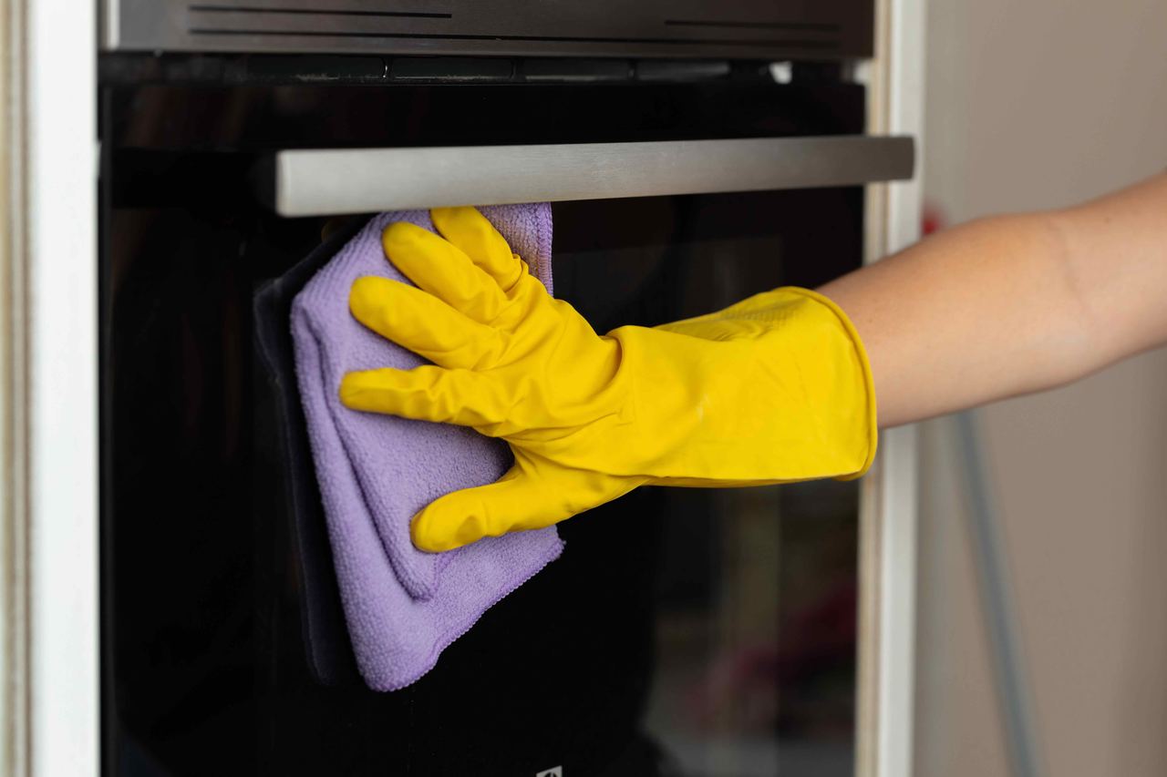 Wiping down an oven door with a microfibre cloth after a professional oven clean