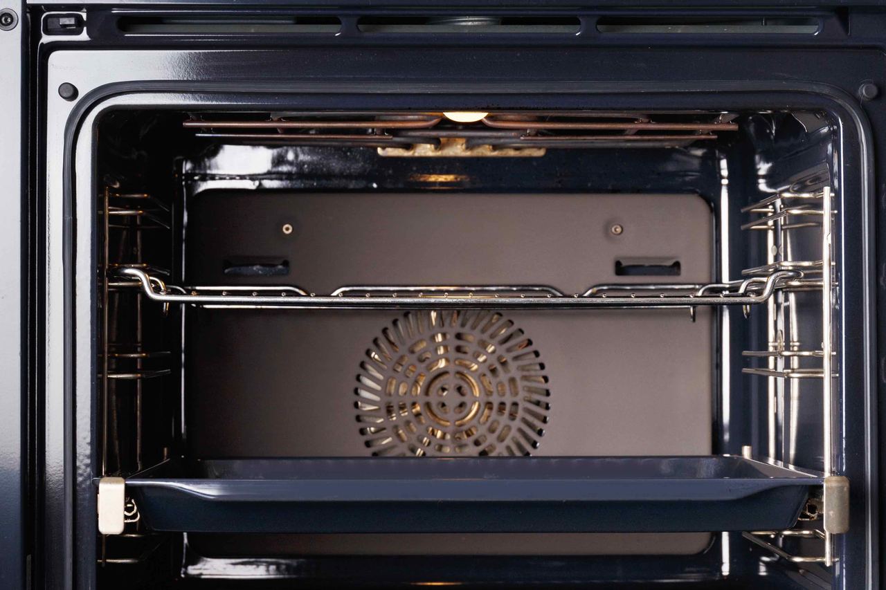 A freshly cleaned built-in oven in a Bognor Regis kitchen, door open, with the racks and base gleaming under a gas hob